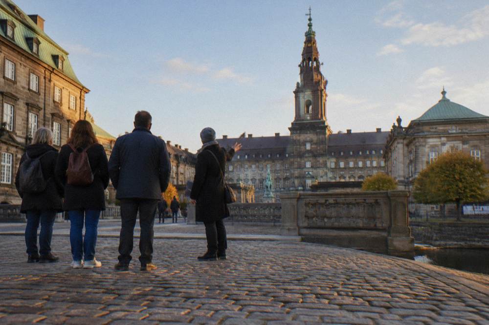 Un guía oficial hablando a un pequeño grupo de visitantes en una plaza de Copenhague