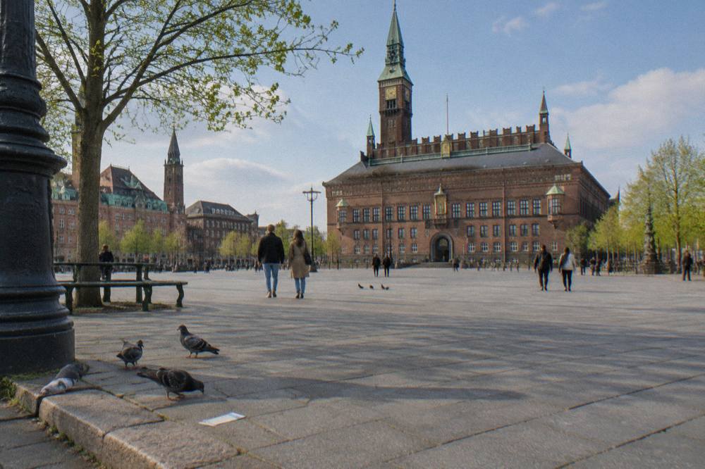 Wide cobblestone square in central Copenhagen with historic civic buildings on all sides