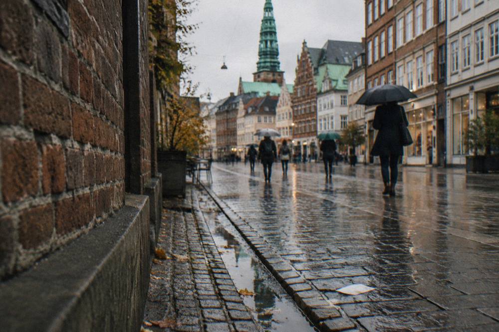 Narrow pedestrian shopping street in Copenhagen lined with old buildings and shopfronts