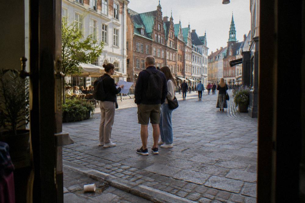 Un guía con un pequeño mapa hablando con turistas en una esquina de Copenhague