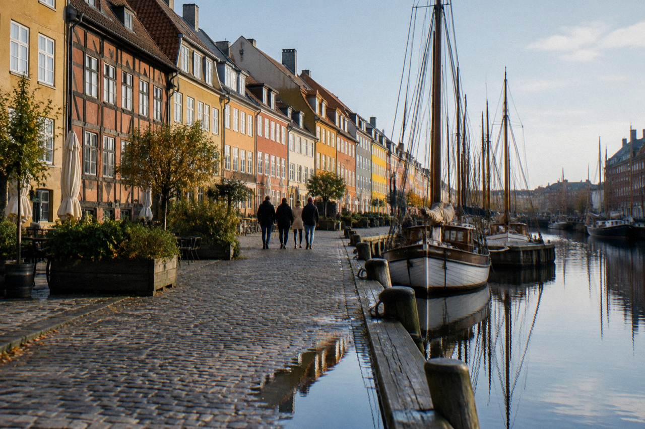 A tour guide speaking to a small group on a cobbled Copenhagen square beside old coloured townhouses