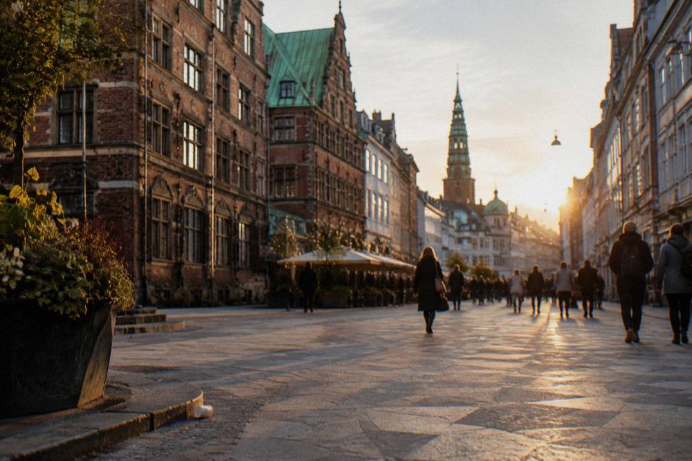 Cyclists crossing a Copenhagen street with old brick buildings on either side