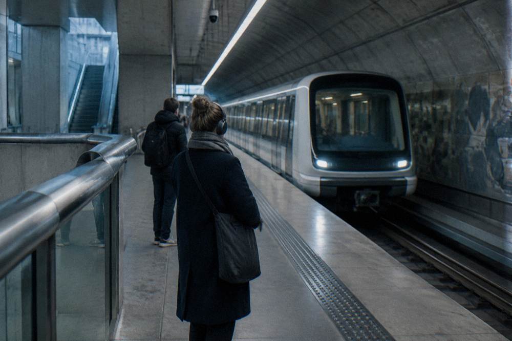 Andén de metro de Copenhague con un tren moderno llegando y algunos pasajeros esperando