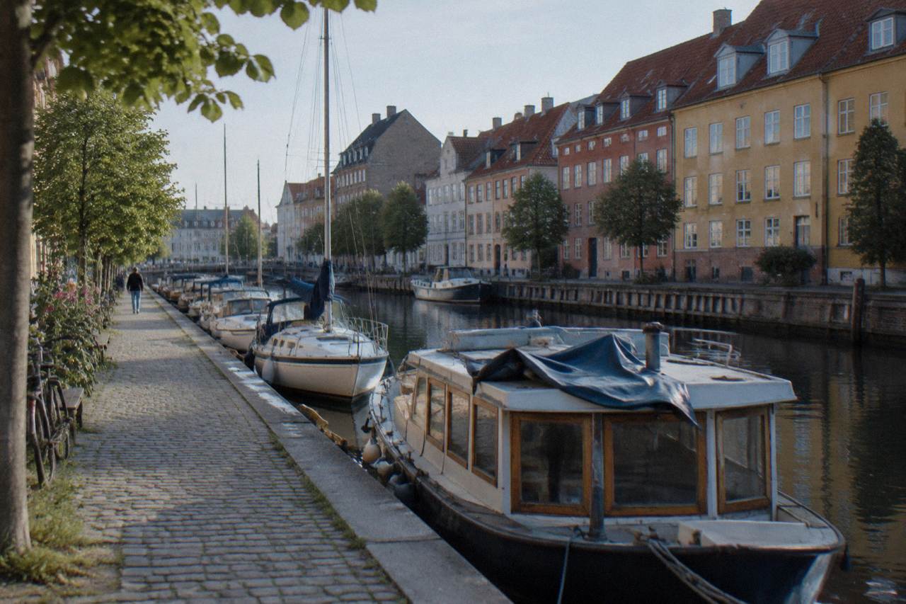 Quiet Copenhagen street with colourful buildings and bicycles parked along the canal