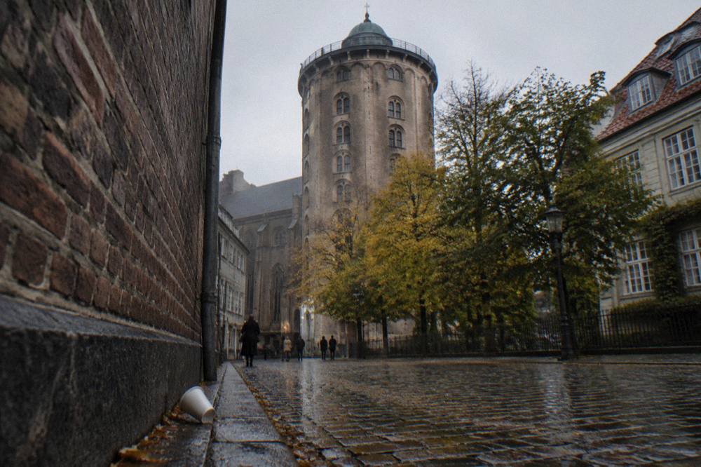 The Round Tower's pale facade seen from the narrow shopping street below