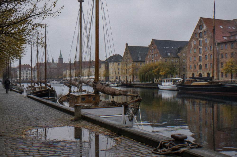 Un canal de Copenhague con barcas amarradas y fachadas de almacenes con frontones