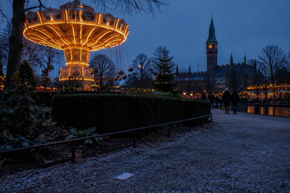 Historic amusement park rides and gardens lit up in the evening