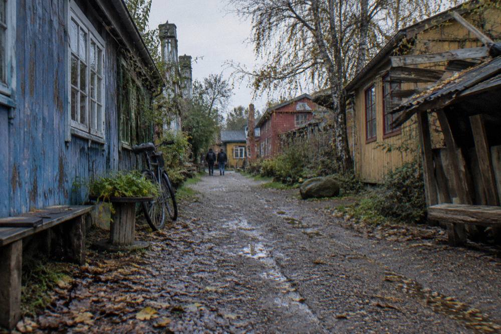 Hand-painted wooden buildings along a gravel lane in Christiania