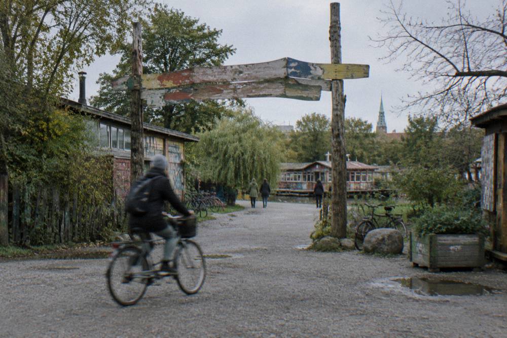 A worn sign at a Christiania entrance stating the local rules for visitors