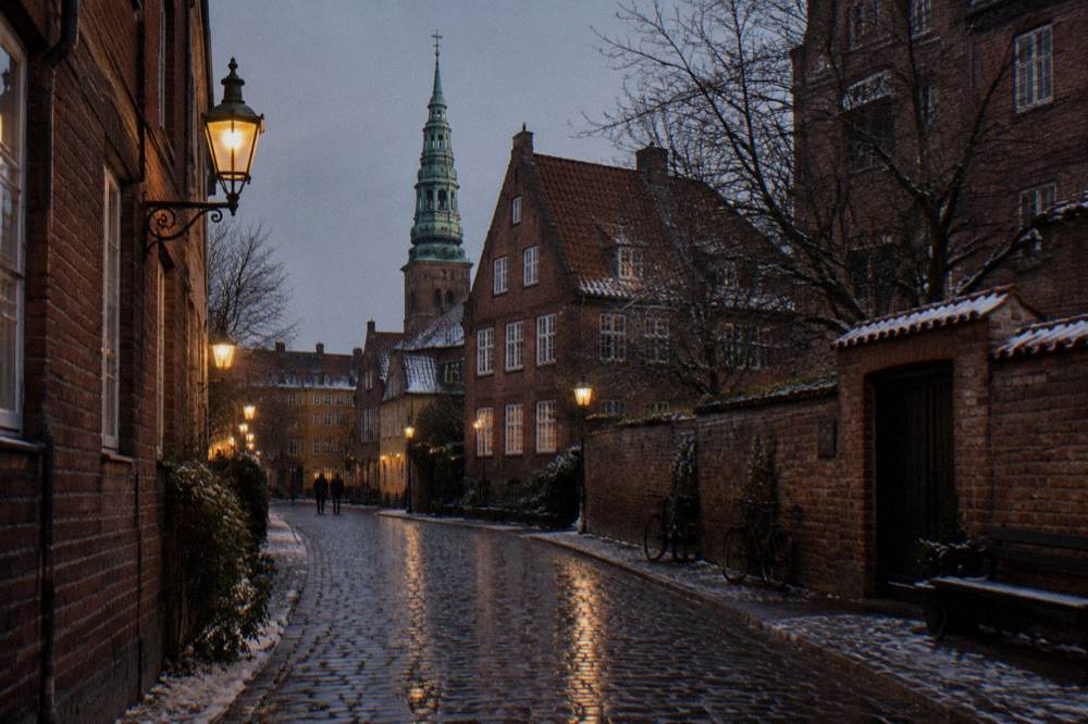 A Copenhagen street at dusk with old lamps glowing on brick facades and wet cobblestones reflecting the light