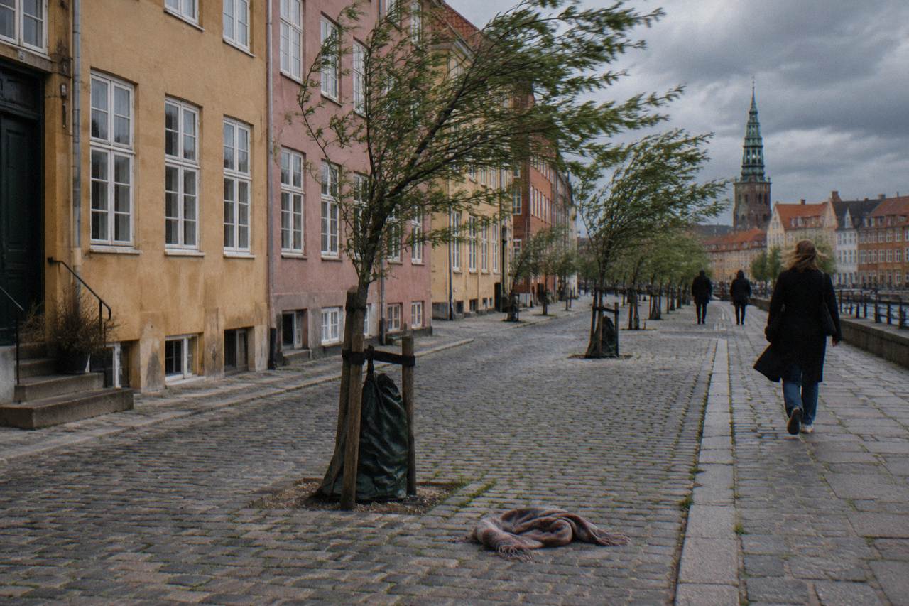 A cobblestone street in central Copenhagen with colourful facades under a cloudy sky