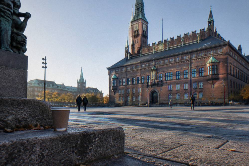 Plaza del Ayuntamiento de Copenhague con la fachada de ladrillo ornamentada y el pavimento abierto en primer plano