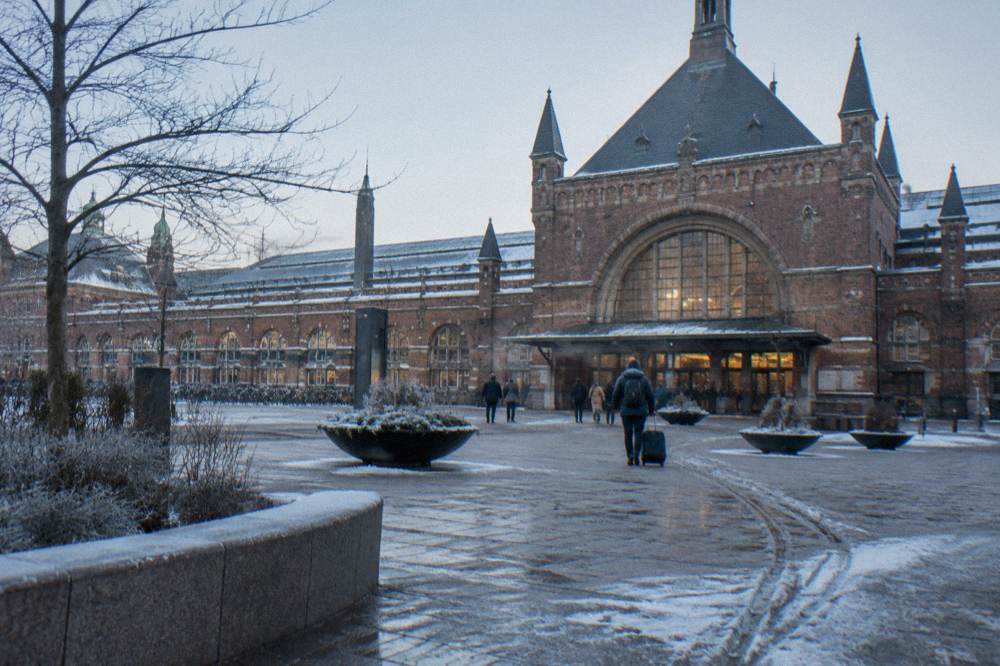 Fachada de la estación central de Copenhague con la entrada abovedada y la plaza abierta al frente