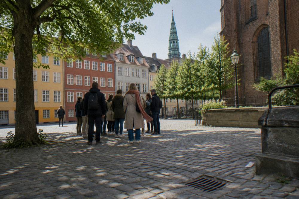 A walking tour group gathered on a cobbled square in the old town of Copenhagen