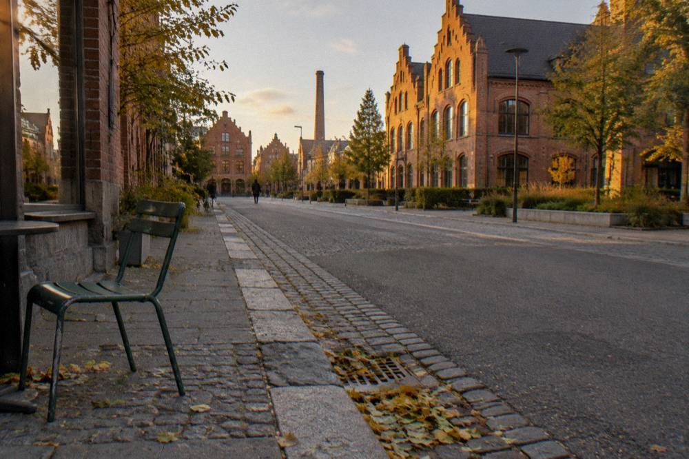 A wide street in Vesterbro with old brick buildings and bicycles parked along the pavement