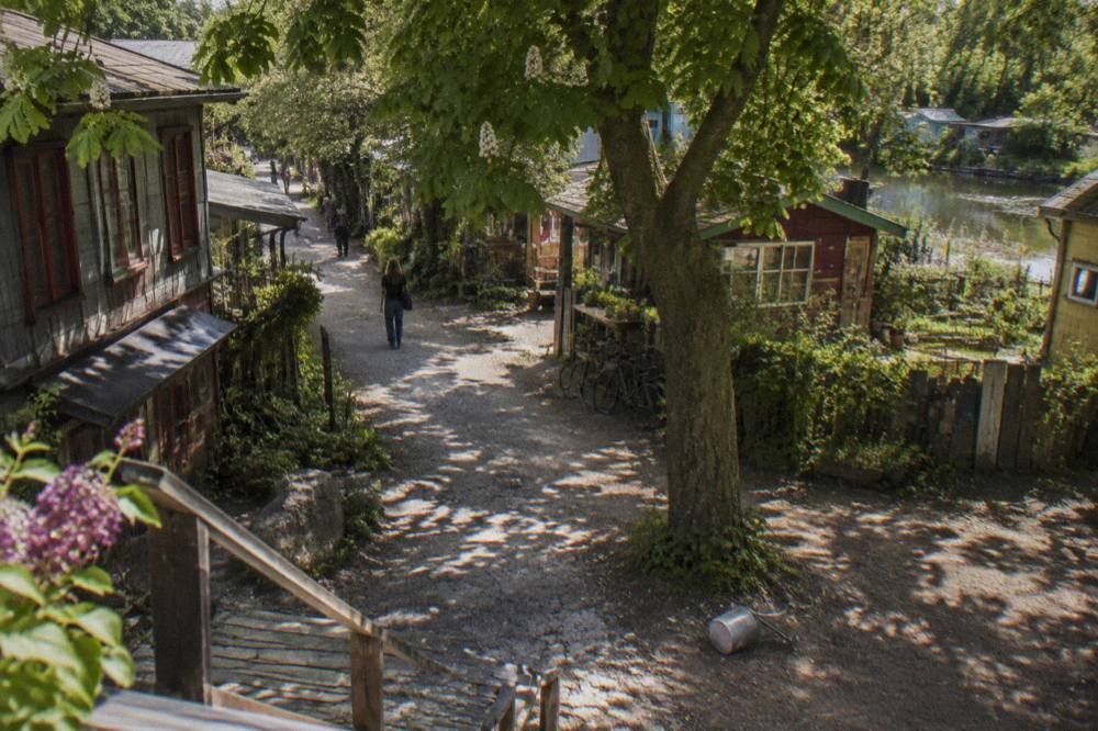 Hand-painted wooden houses and trees along a quiet lane in Christiania