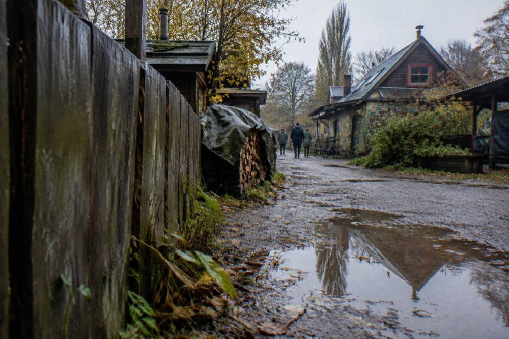 Gravel street with weathered wooden fences and painted signage in Christiania