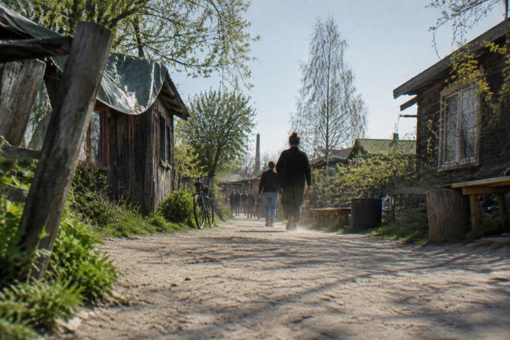 Wide dirt path lined with small wooden buildings and bicycle traffic