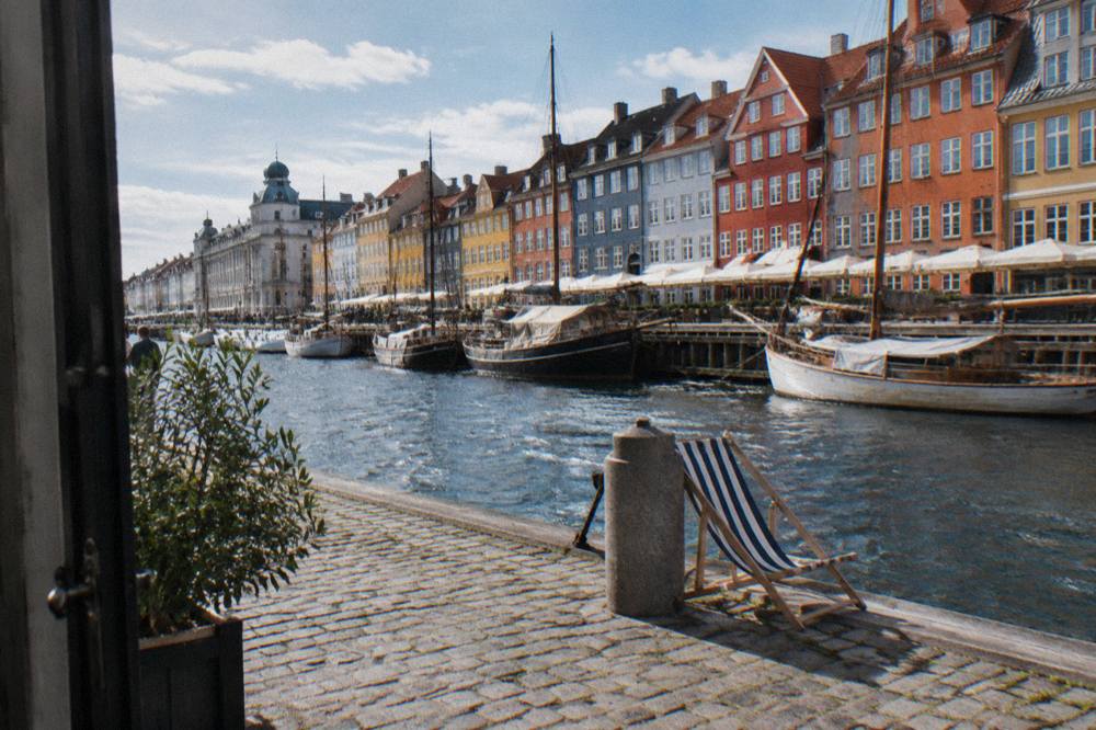 Narrow colourful townhouses reflected in the Nyhavn canal on a bright day