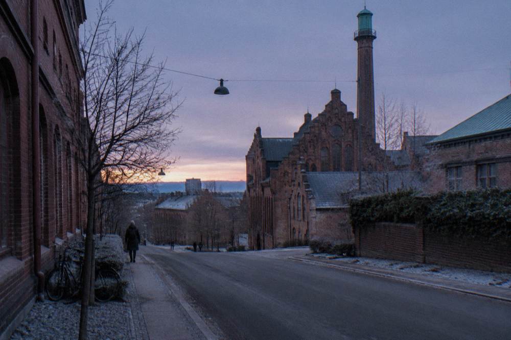 Old brick brewery buildings and a wide street in the Carlsberg district at dusk