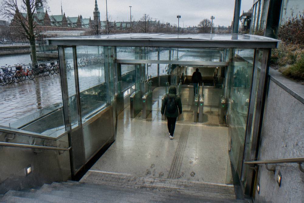 A ticket machine and metro entrance at a Copenhagen station with a traveller at the gates
