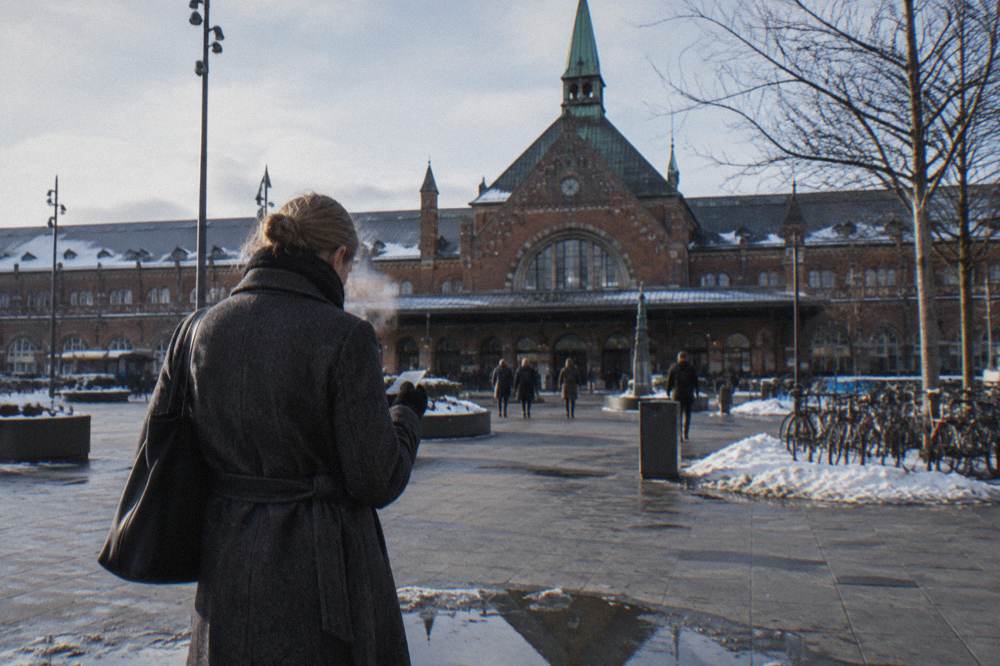 A visitor comparing a transit pass and a museum entrance on a bench outside a Copenhagen station
