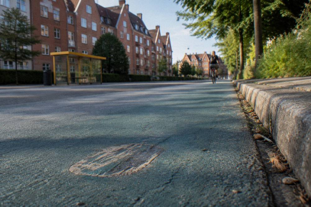 Cyclists on a painted Copenhagen cycle lane passing a bus stop
