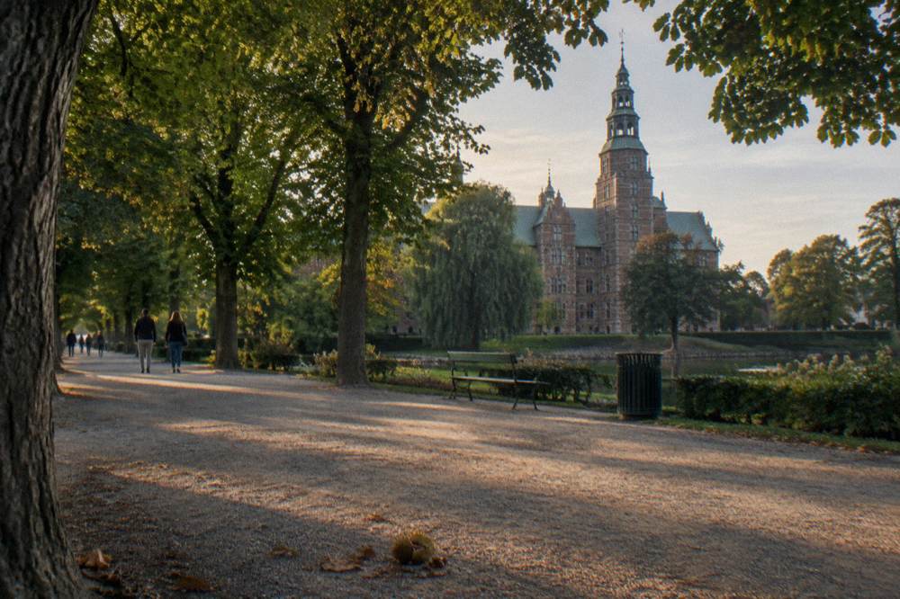 Garden path with mature trees and a historic castle in the background