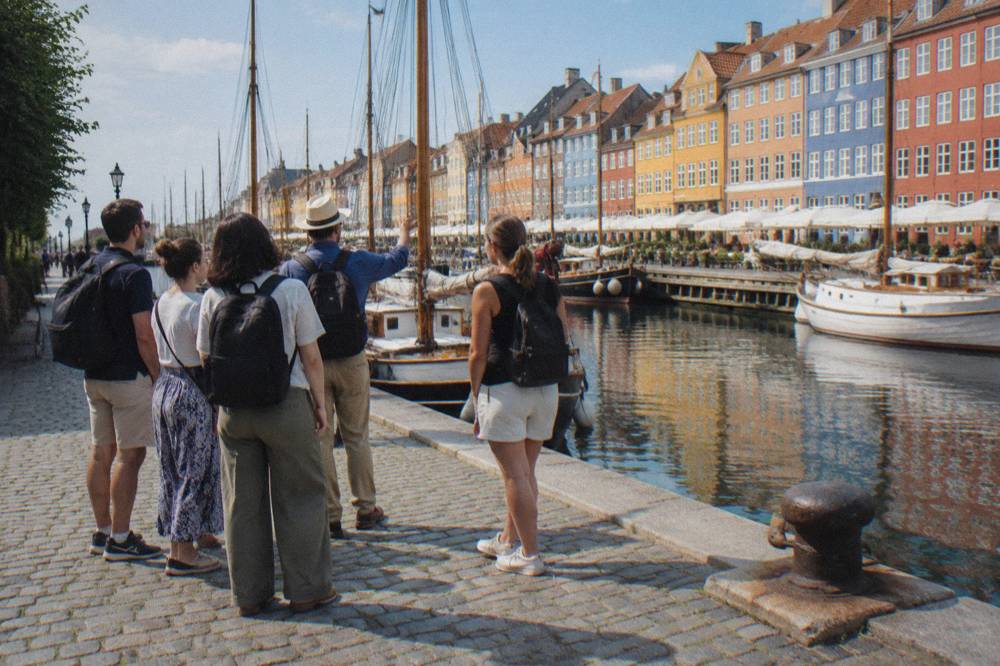 A guided walking group pausing on a cobblestone street near the old harbour in bright daylight