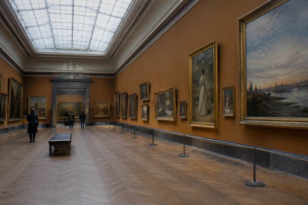 Grand gallery hall with paintings hung in rows under a skylight