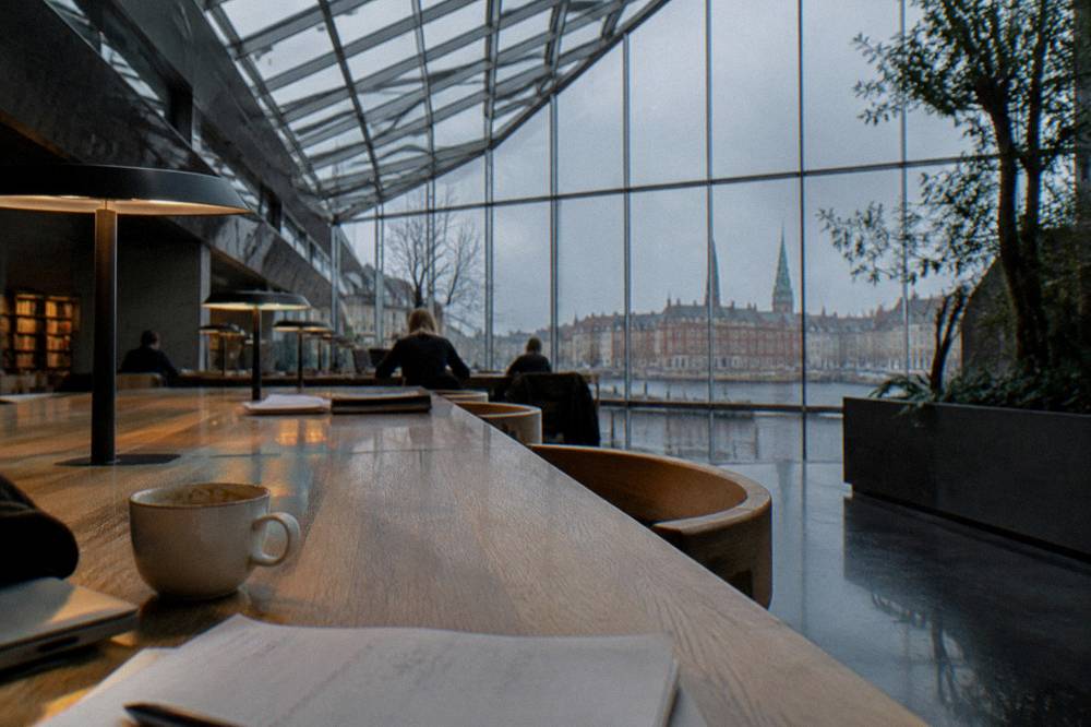 Reading room with long wooden desks and bookshelves under an atrium ceiling