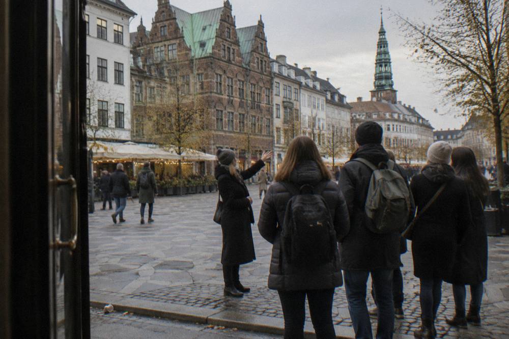 A walking guide speaking to a gathered group beside an old Copenhagen building