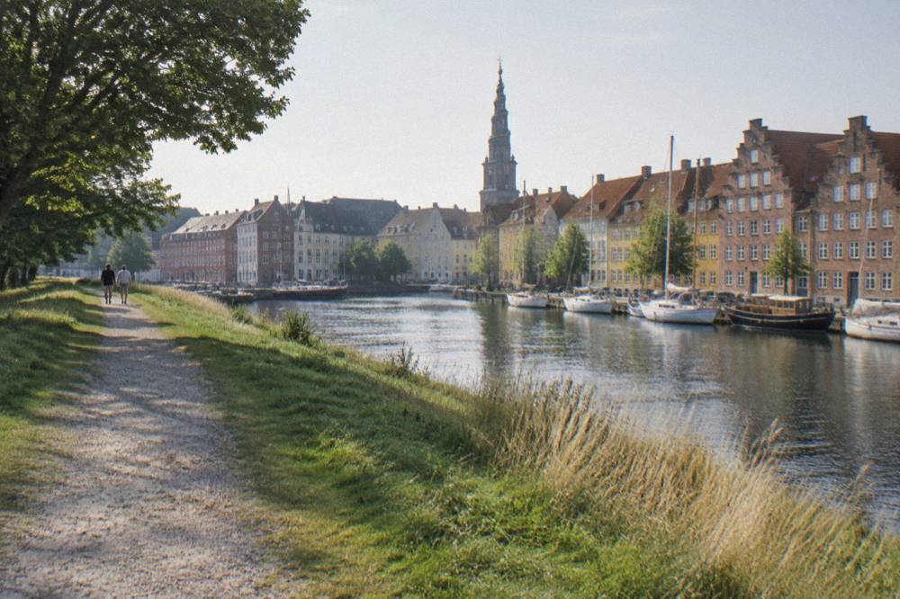 Grassy rampart path in Christianshavn with canal houses and a church spire beyond