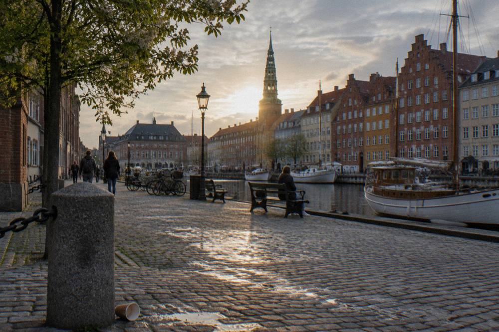 A cobblestone square in central Copenhagen with old merchant buildings and a church spire