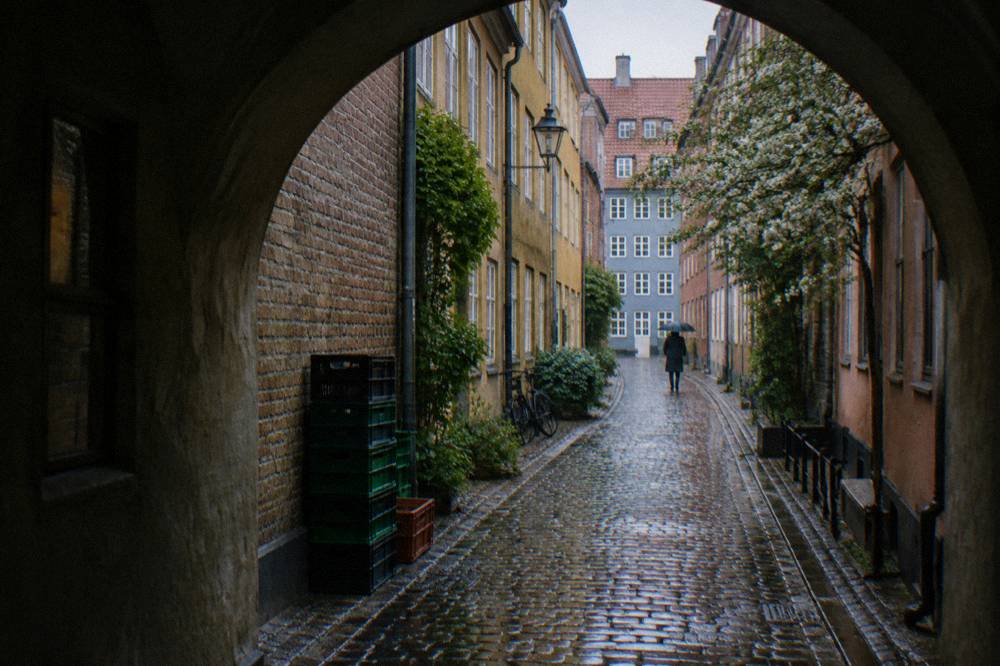 A narrow old street in Copenhagen's inner city with pastel facades and bicycles parked against a wall