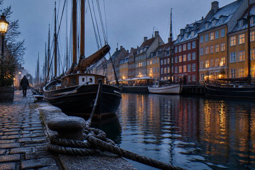 Colourful old townhouses along the Nyhavn canal with masted wooden ships moored alongside