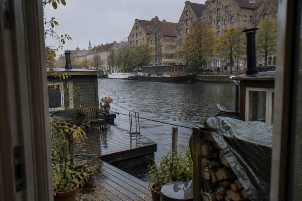 Canal in Christianshavn with houseboats moored along the water and old warehouse buildings on the bank