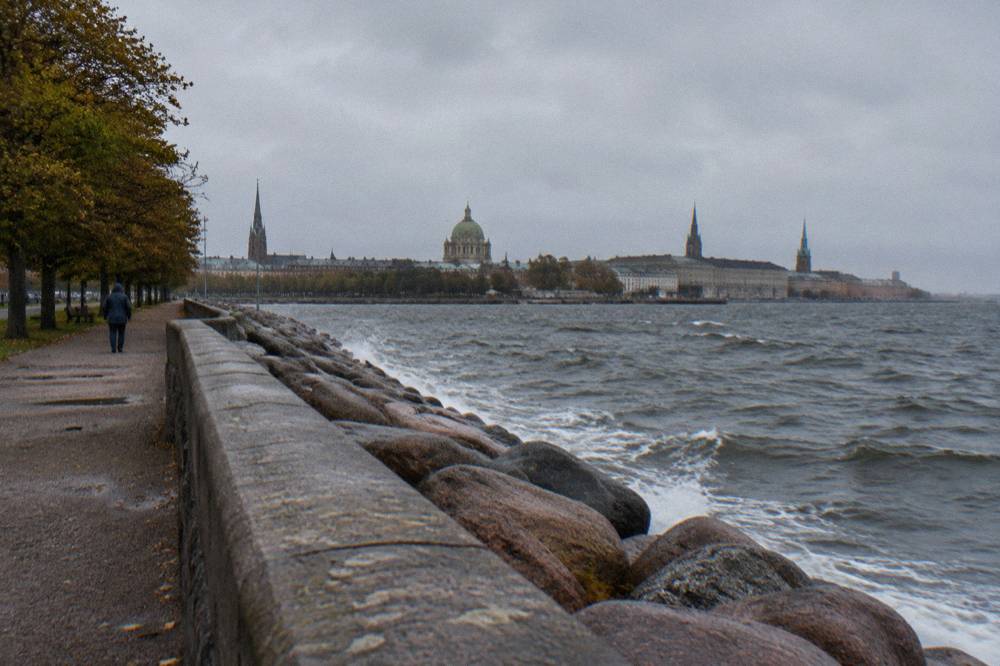 The bronze Little Mermaid statue sitting on a rock at the water's edge in Copenhagen harbour