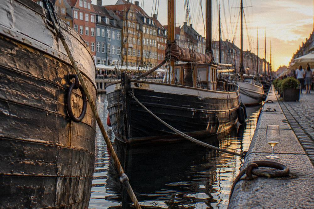 Wooden heritage ships moored along a canal quay with coloured townhouses behind them