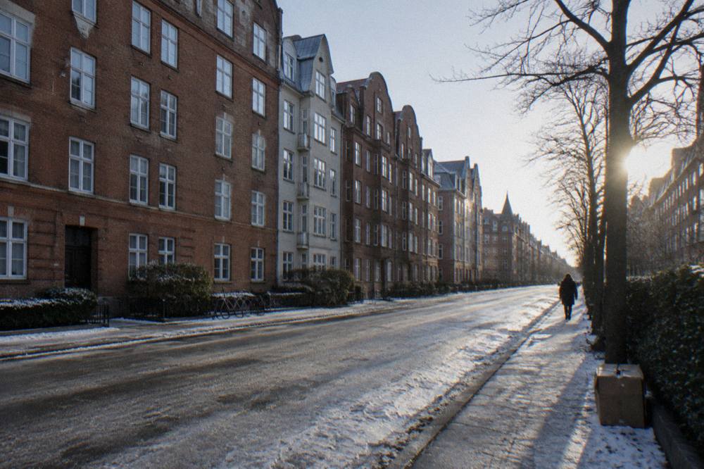 A wide Copenhagen street with old brick apartment buildings and bicycles parked along the pavement
